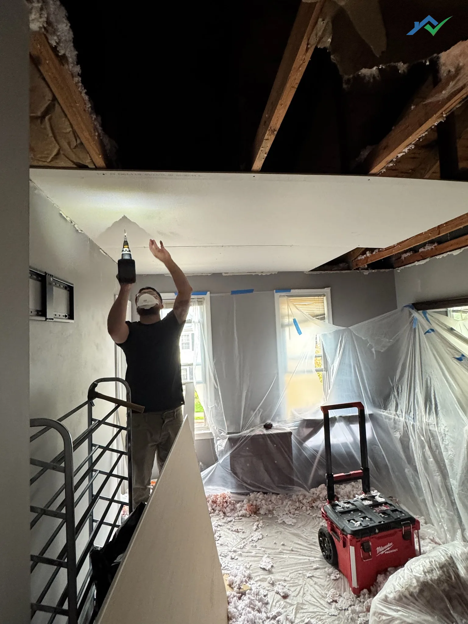 New drywall being screwed to the exposed ceiling joists during the Burke ceiling rebuild.