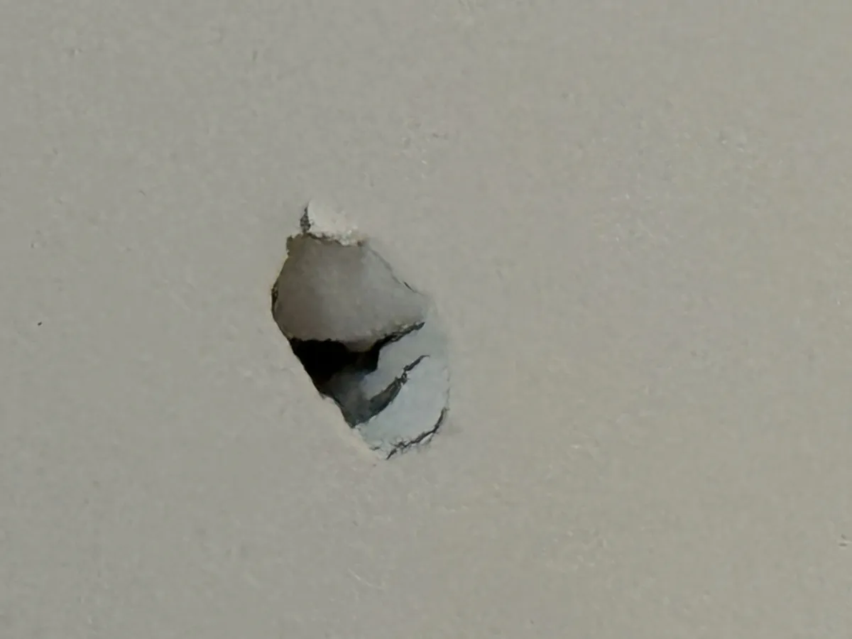 Close-up of ceiling damage showing cracks and peeling drywall before repair