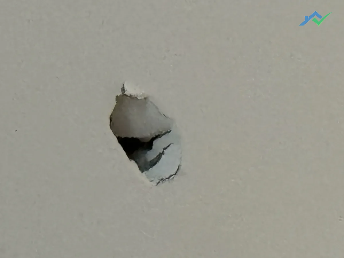 Close-up of ceiling damage showing cracks and peeling drywall before repair