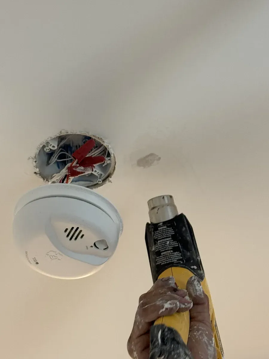 HouseWorks tech Eduardo applying joint compound to ceiling patch in Ashburn VA home