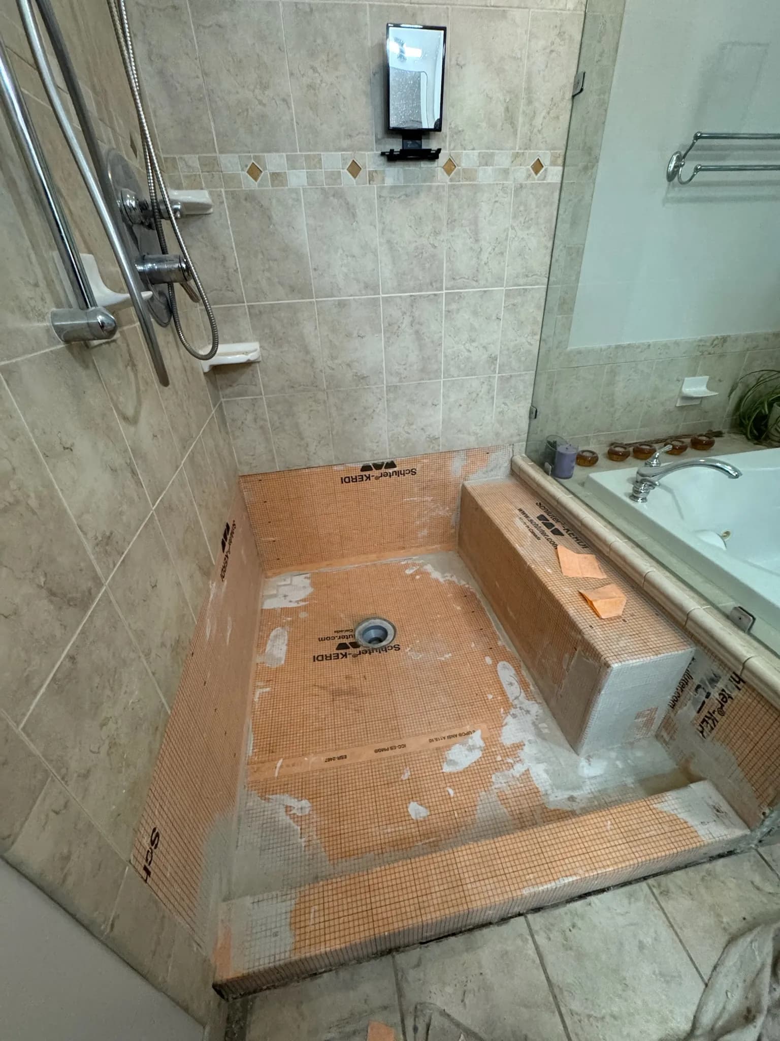 Schluter waterproofing membrane over the rebuilt pan, bench, and walls before tile.