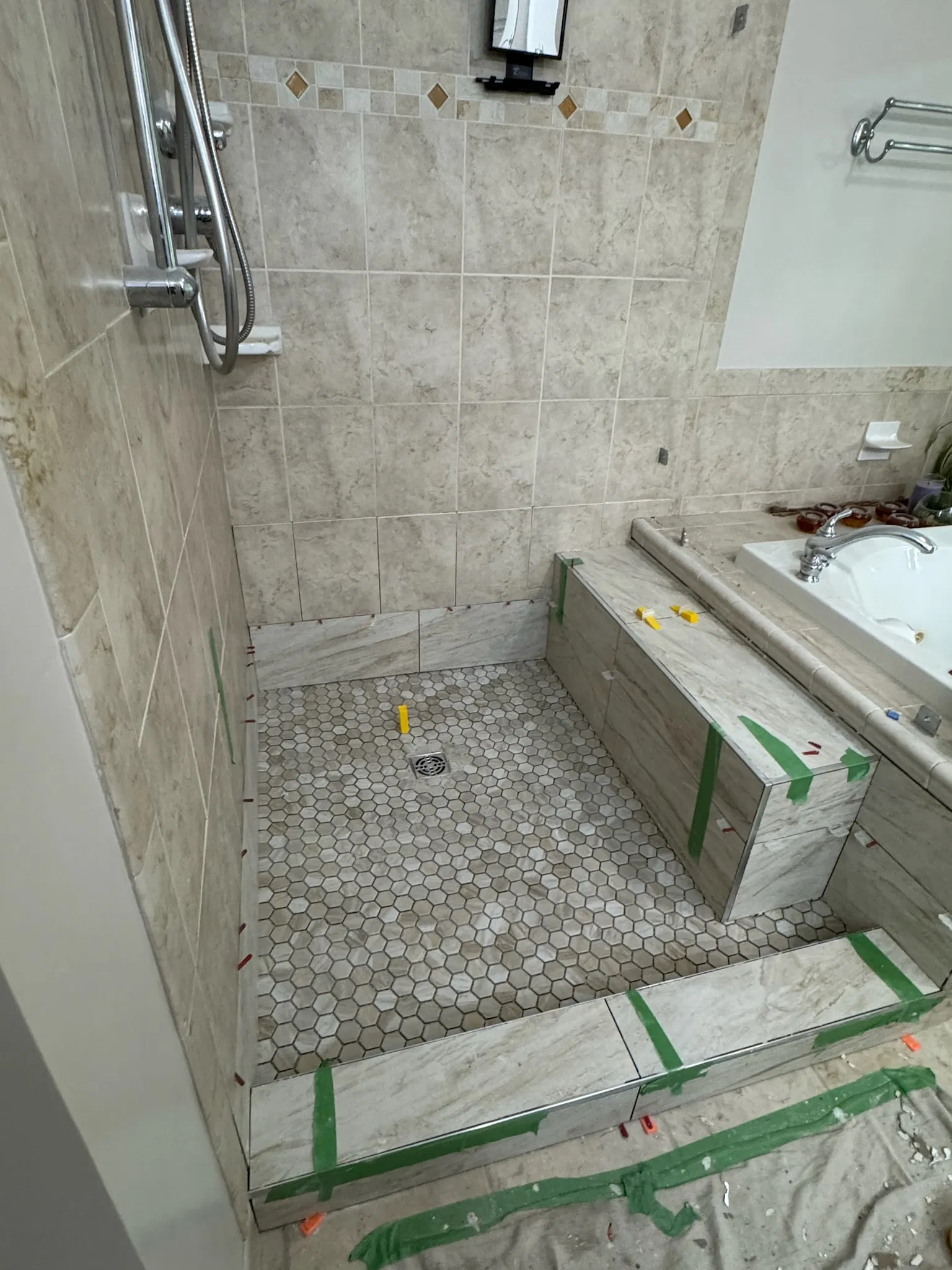 New tile set on the shower walls and hexagonal mosaic floor, ready for grouting and sealing.