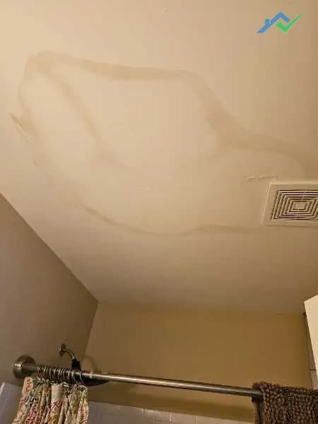 Before shot of Purcellville, VA bathroom ceiling before HouseWorks arrived — a wide brown water stain spread across the ceiling around a bath fan vent, evidence of an old leak that had never been sealed and painted properly.