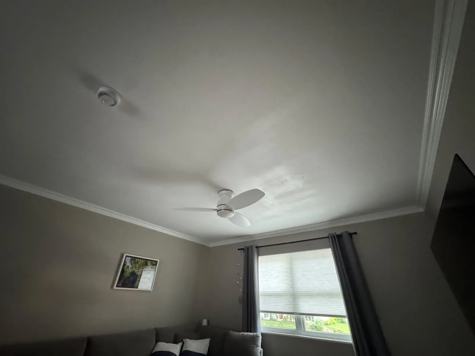 Finished living room ceiling in Herndon, VA after HouseWorks repair — smooth painted surface around the ceiling fan and recessed light, no visible seams or patches from the drywall work.